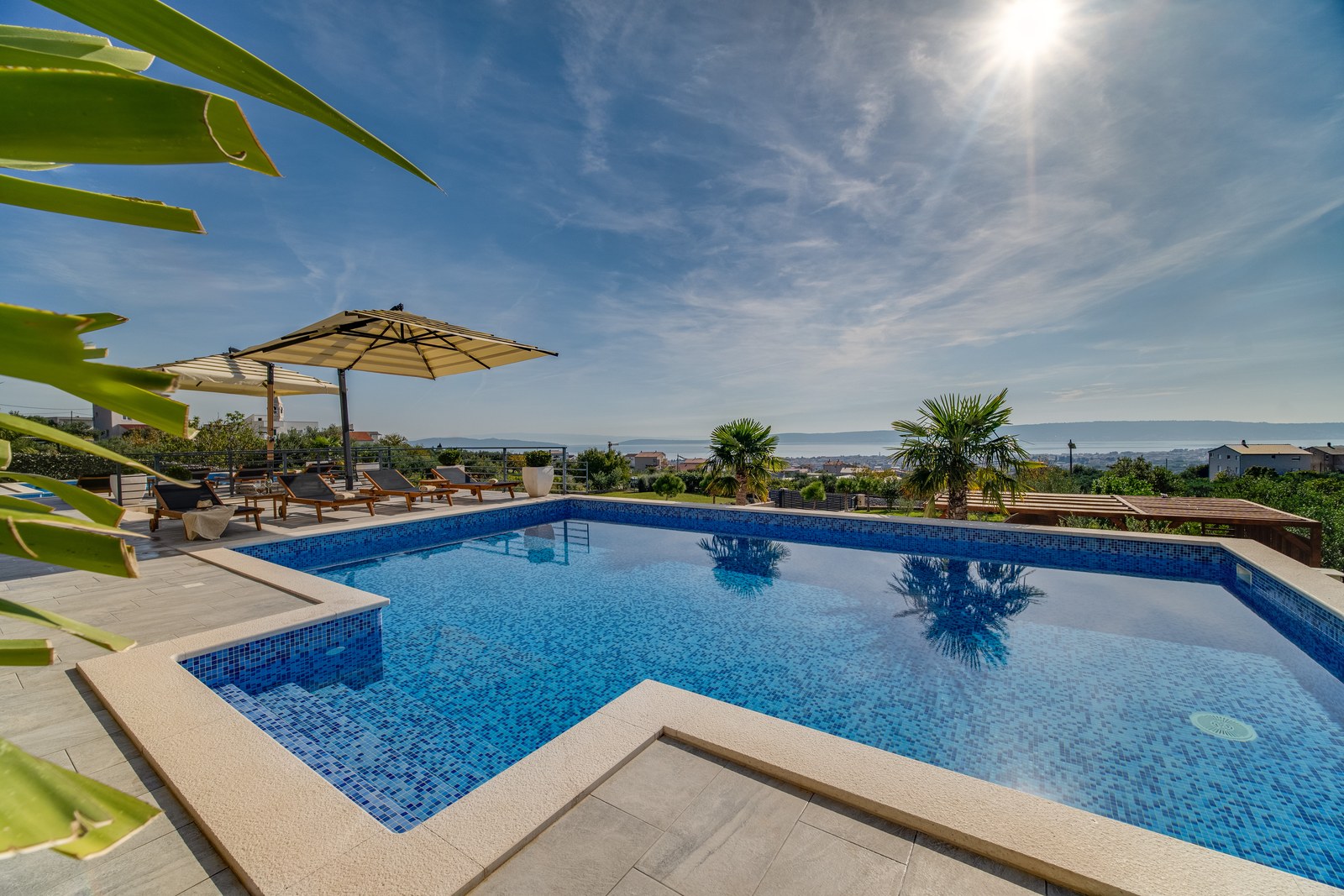 Blue mosaic swimming pool and sun loungers overlooking the Adriatic Sea at Villa BlueWave