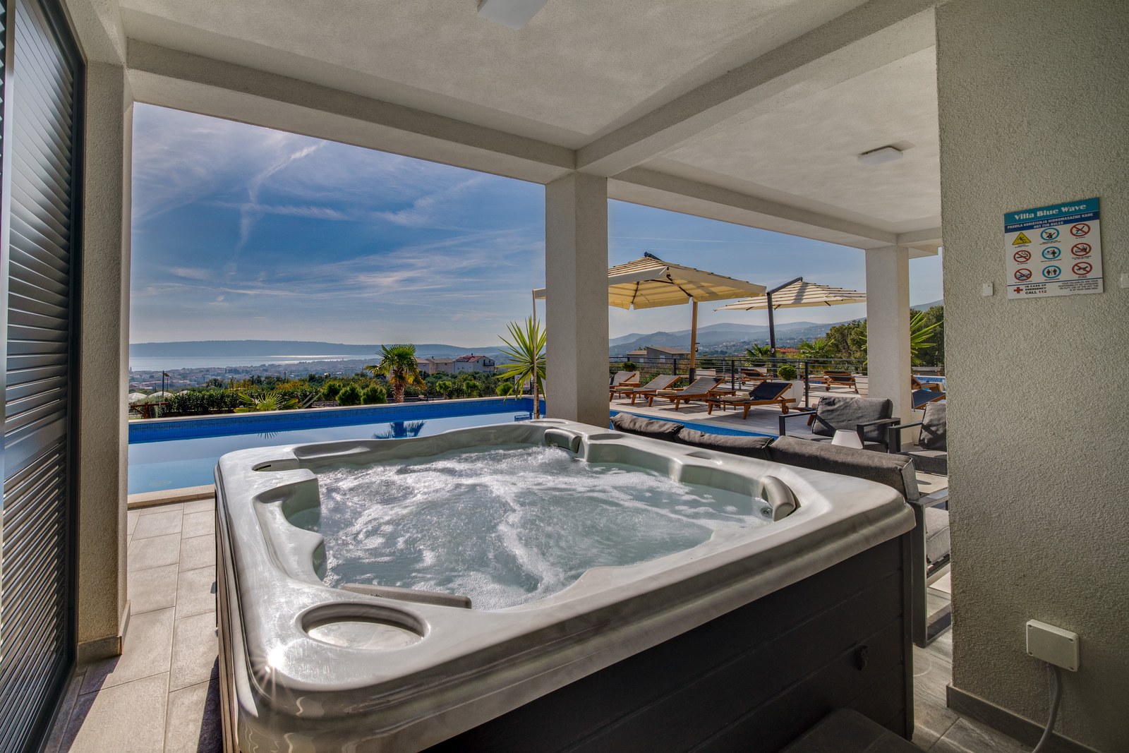 Bubbling six-person jacuzzi on a covered terrace beside the pool