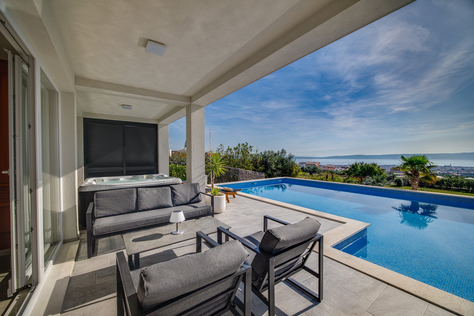 The second swimming pool beside shaded black terrace seating and a hot tub, overlooking the Adriatic Sea.