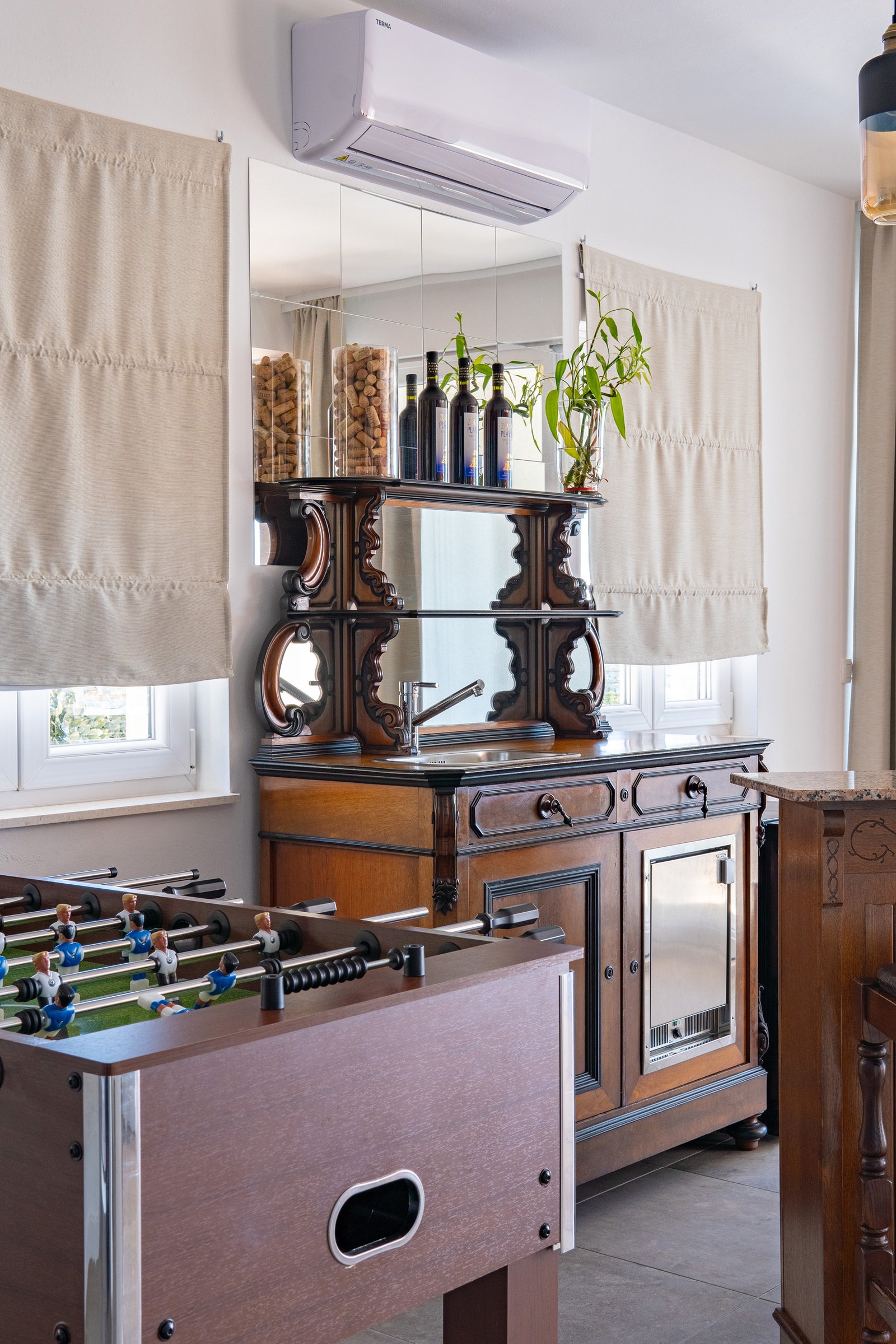 Detail of a table football game in front of the carved wooden bar cabinet and mirrored bottle shelf.